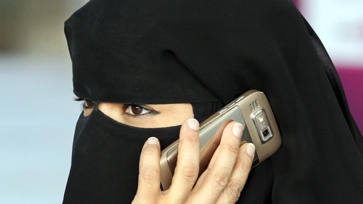 Woman wearing a niqab, talking over a mobile phone (phone: dpa/picture-alliance)