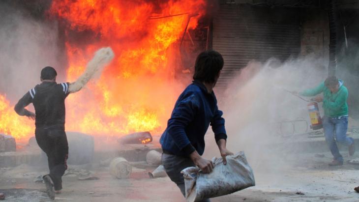 عدد من سكان مدينة حلب شمال سوريا يحاولون إطفاء النار المشتعلة في محل للغاز والمازوت في منطقة بستان القصر بتاريخ 20 أكتوبر/ تشرين الأول 2013. وقال شاهد عيان إن الحريق تسببت به رصاصات مسلح موالٍ  للرئيس السوري بشار الأسد. photo: Reuters 