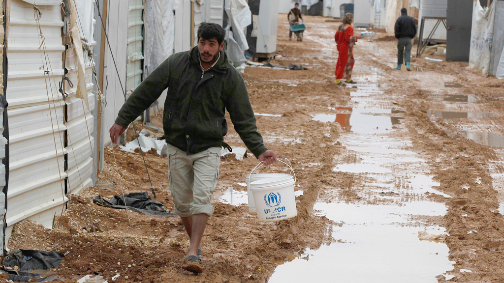 A Syrian refugee walks to collect water after heavy rain at Al Zaatari refugee camp in the Jordanian city of Mafraq (photo: picture alliance/AP Photo)