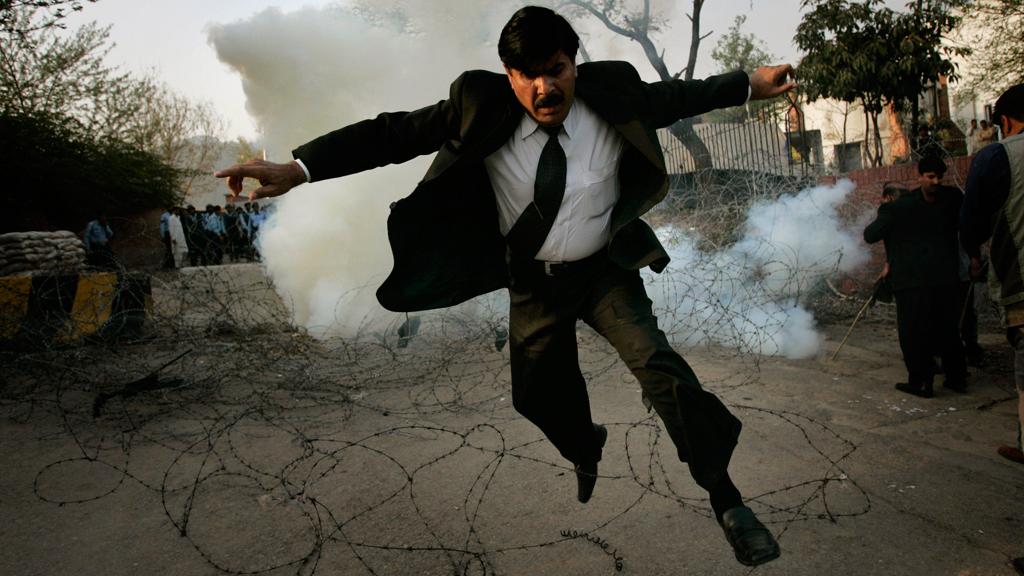 In this March 9, 2008 file photo, a Pakistani lawyer runs away from tear gas fired by police officers outside the residence of the country's deposed chief justice Iftikhar Mahmood Chaudhry during a protest in Islamabad (AP Photo/Emilio Morenatti)