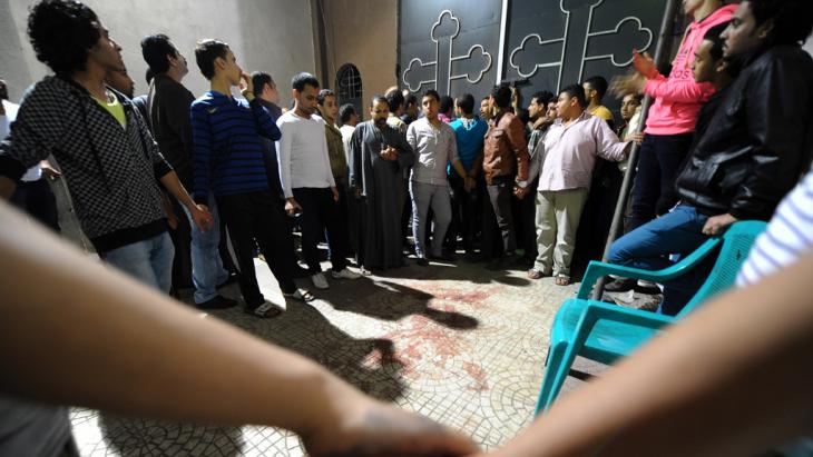 مصريون متجمعون عند كنيسة قبطية في القاهرة بتاريخ 20 أكتوبر/ تشرين الأول 2013 بعد مقتل امرأة وإصابة آخرين برصاص رجل يركب دراجة نارية. photo: AP/Mohsen Nabil