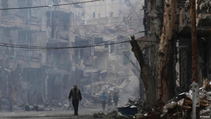رجل يمشي وحوله أنقاض البنايات في أحد شوارع مدينة دير الزور السورية. photo: Reuters