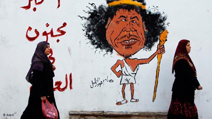 جدارية يظهر عليها رسم كاريكاتوري للزعيم الليبي الراحل معمر القذافي ومكتوب فيها: أكبر مجنون في العالم. photo: EPA/Getty Images