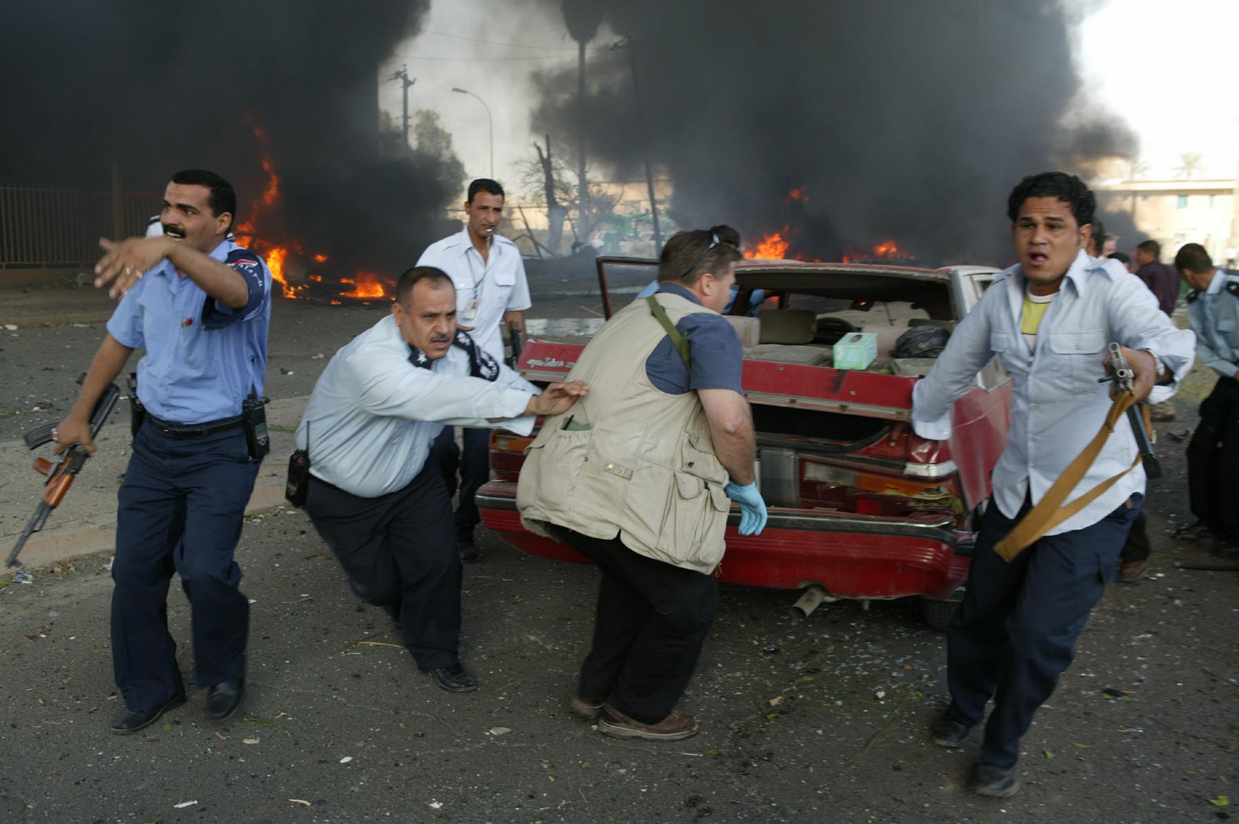 Männer bergen einen Wagen nach einem Sprengstoffanschlag eines Selbstmordattentäters vor dem Gebäude des Internationalen Roten Kreuzes in Bagdad im Oktober 2003; Foto: Michael Kamber