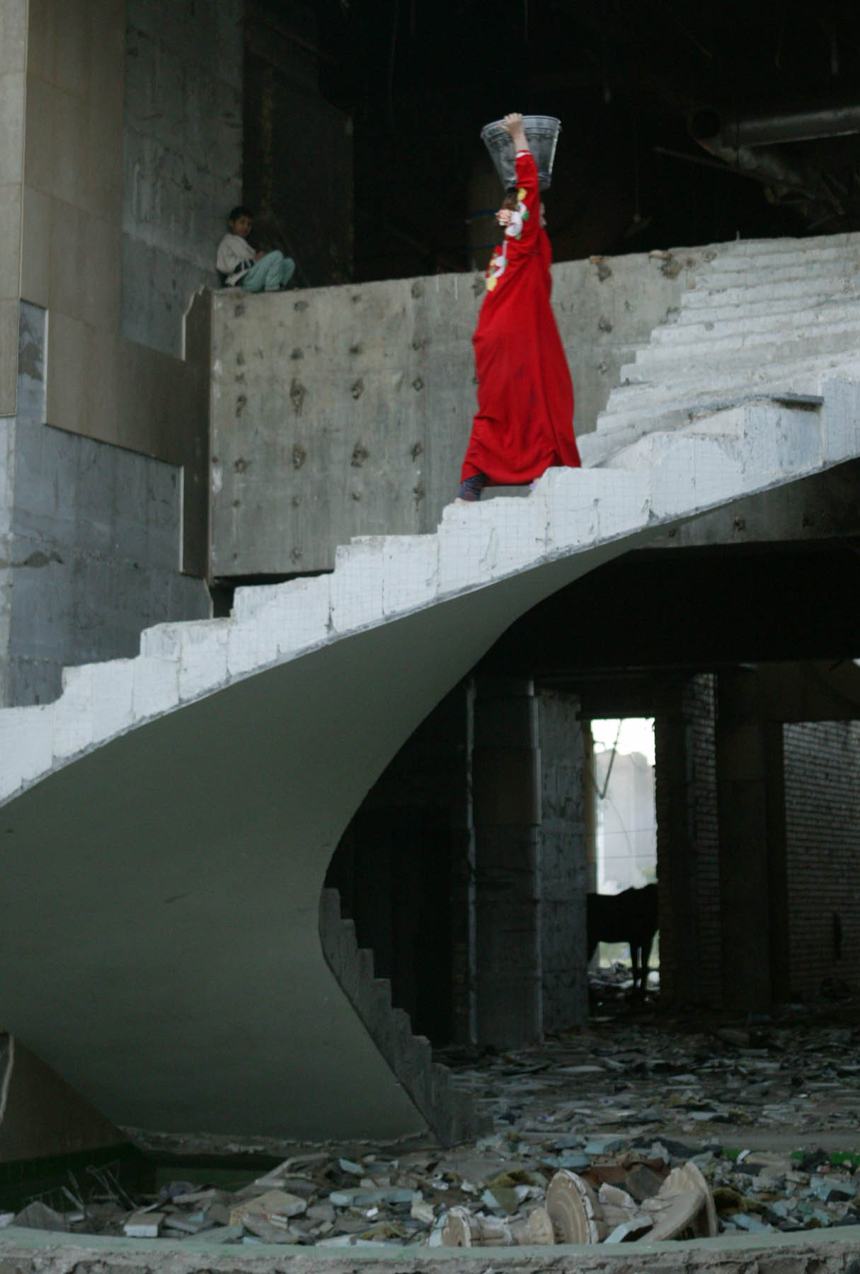 A woman walks up the stairs of the ruined Baghdad Iraqi Air Force Club while a child looks on (photo: Michael Kamber)