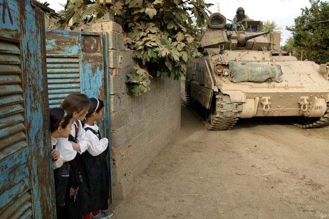 Schoolgirls watch US soldiers driving by in a tank (photo: Michael Kamber) 
