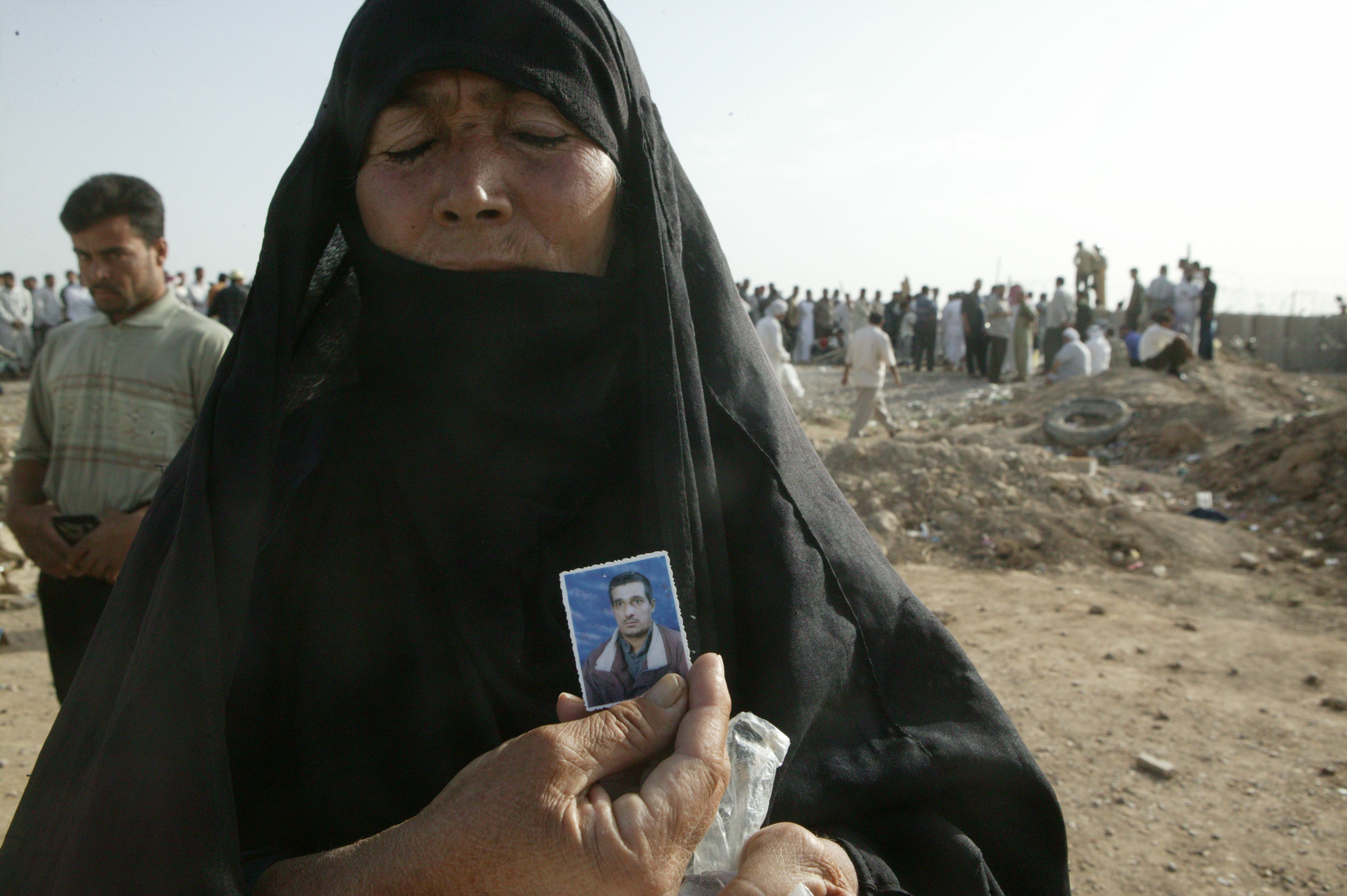 A woman holds up a photo of her son outside Abu Ghraib (photo: Michael Kamber)