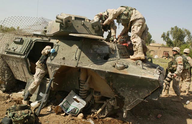 US soldiers pull the driver from an armoured vehicle destroyed by an IED (photo: Michael Kamber)