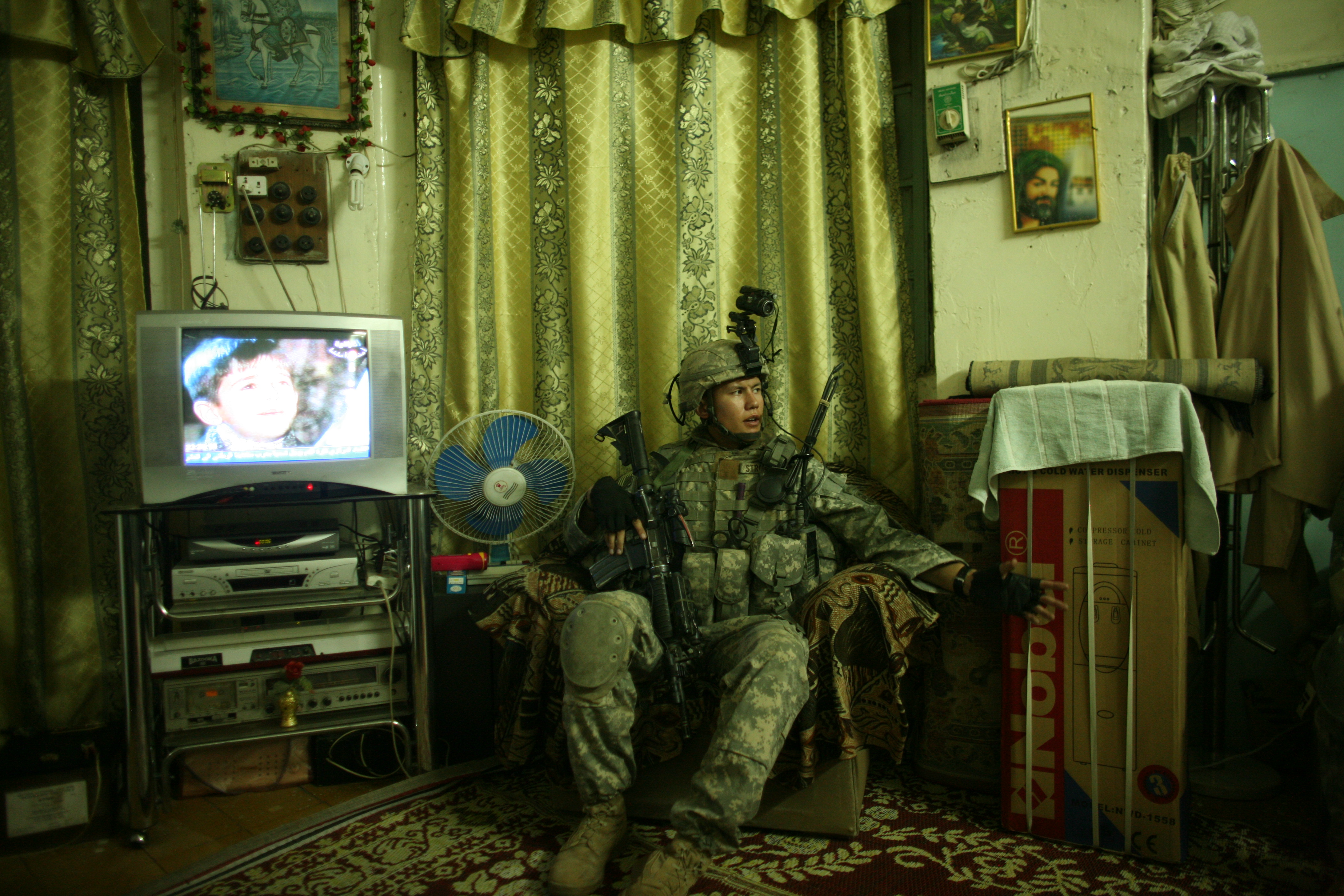 A US soldier sits in an armchair during a search of a private home (photo: Michael Kamber)