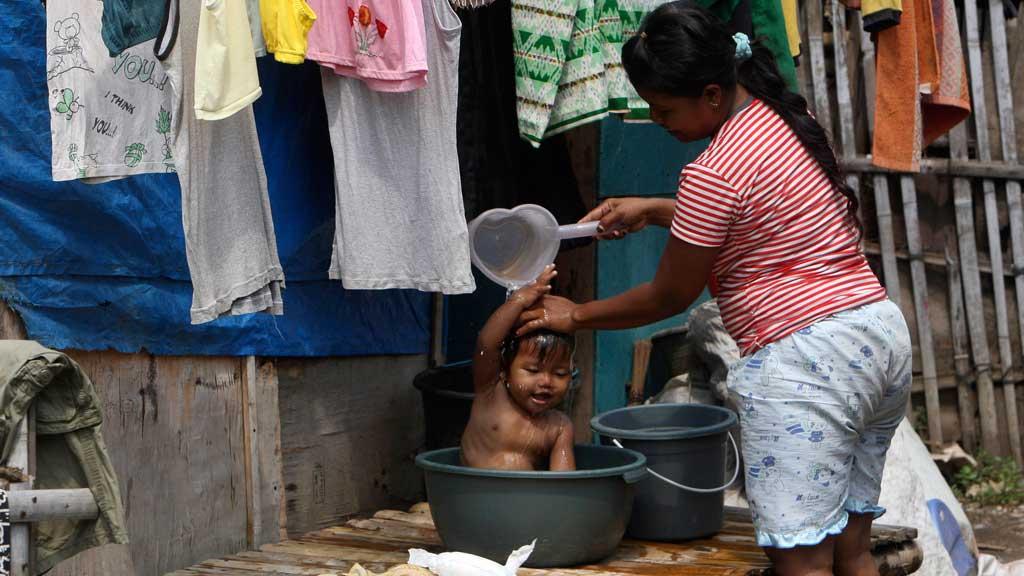 Eine Frau wäscht ihr Kind vor ihrer Hütte in einem Slum in der indonesischen Hauptstadt Jakarta; Foto: AP