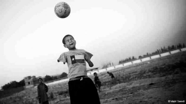 A boy with no arms jumps up to head a football (photo: Majid Saeedi)