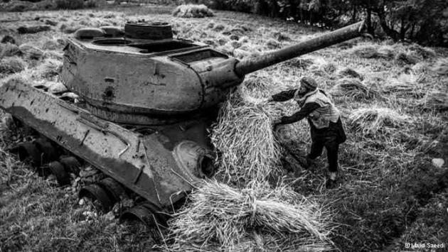 A farmer piles bundles onto a Soviet tank in his field (photo: Majid Saeedi)