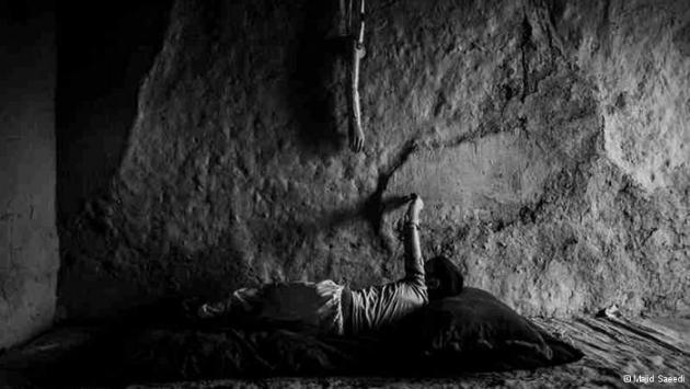 A child looks at his prosthetic arm hanging on a wall (photo: Majid Saeedi)