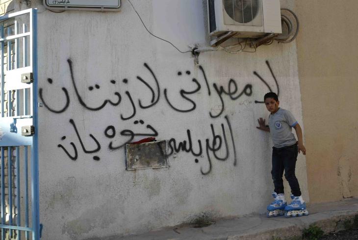 A boy on roller skates in front of graffiti that reads "No Misrata, no Zintan" (photo: Valerie Stocker)