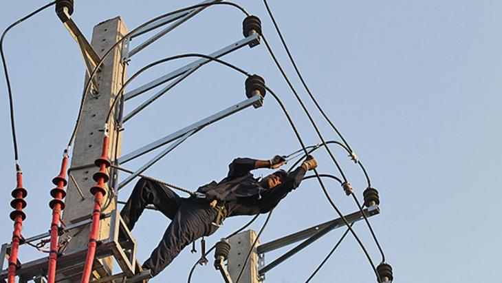 An Afghan worker repairing an electricity pylon in Tehran (photo: INLA)