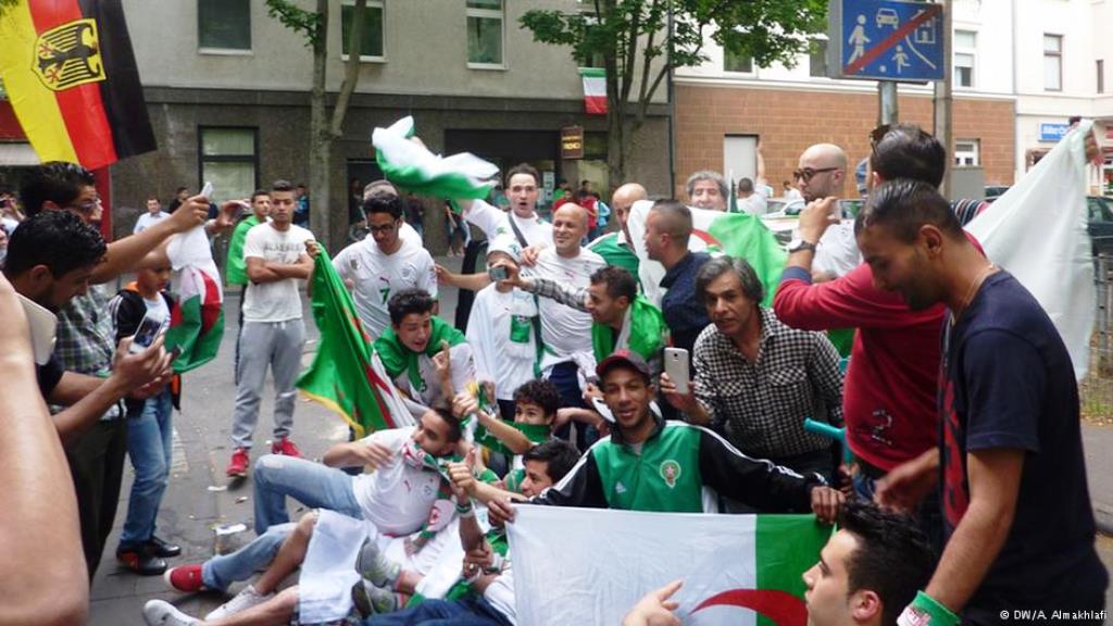 فرحة بعد تسجيل الهدف الجزائري والعلم الألماني حاضر إلى جانب العلم الجزائري في كولونيا