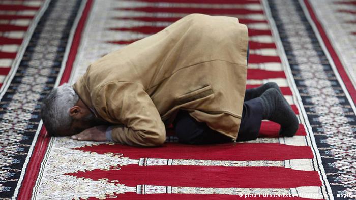 Man praying on a red carpet in Amman airport. Photo: picture alliance/Robert Harding World Imagery