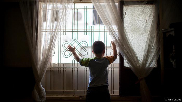 A Syrian-Armenian child refugee standing at a window in Beirut (photo: Amy Leang)