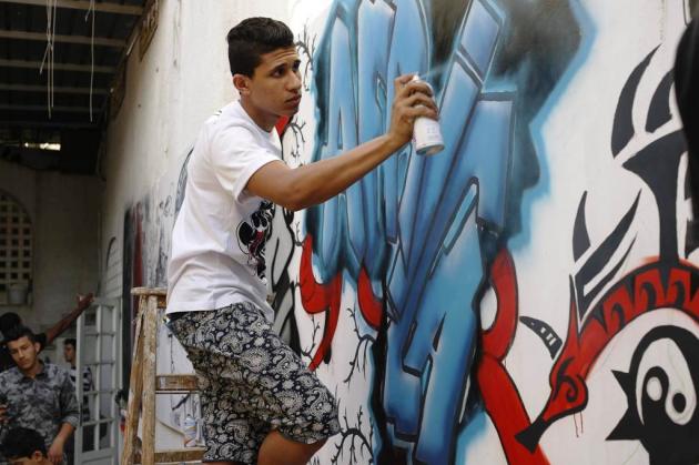 Young graffiti artists in front of a mural at a bombed-out Libyan military base (photo: Valerie Stocker) 