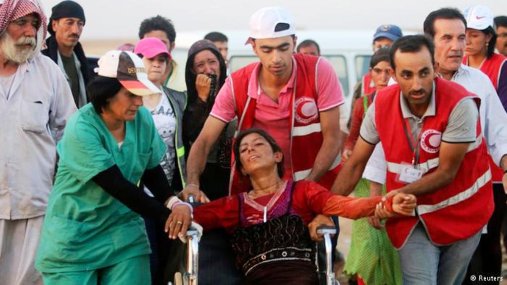 بعض المتطوعين الأكراد في منظمة الهلال الأحمر يقدمون الإسعافات الأولية للاجئين الأيزيدين