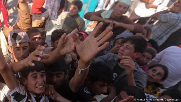 Desperate refugees reaching up for water (photo: Ahmad Al-Rubaye/AFP/Getty Images)