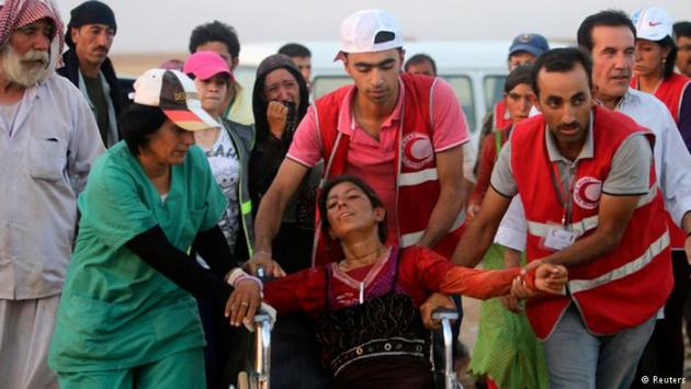 Members of the Red Crescent help a Yazidi woman (photo: Reuters)