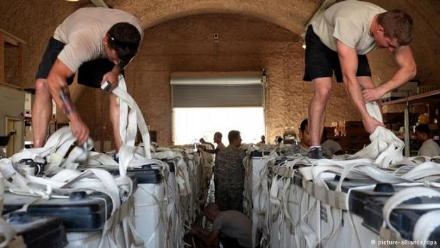 US Army soldier parachute riggers prepare pallets of water for a humanitarian air drop, 6 August 2014 (photo: picture-alliance/dpa)