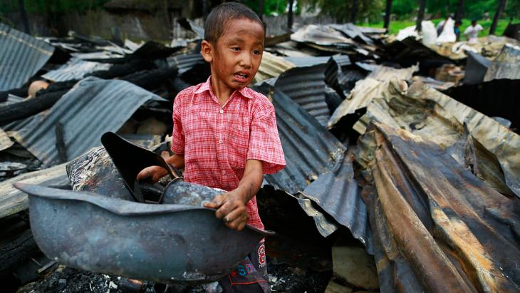 A boy salvages belongings from a burned-down building in Htan Kone village in Myanmar's northern Sagaing region on 25 August 2013 (photo: Reuters)