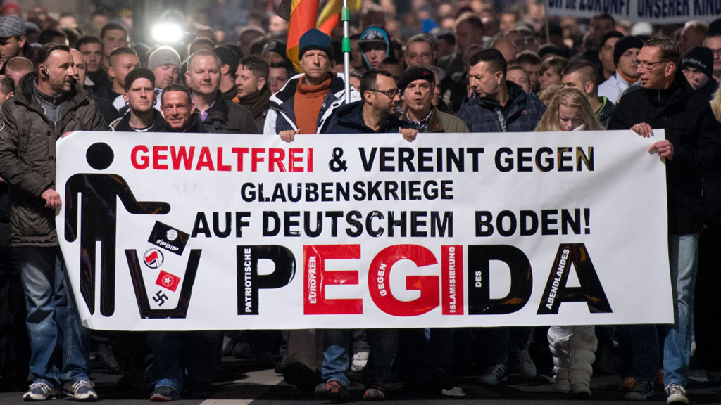 People marching behind a banner reading "non violent and united against religious wars on German soil! PEGIDA" (photo: picture-alliance/dpa/Arno Burgi) 