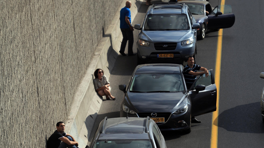 Israelis take cover near their cars while sirens sound over Tel Aviv, 9 July 2014 (photo: picture-alliance//Landov)