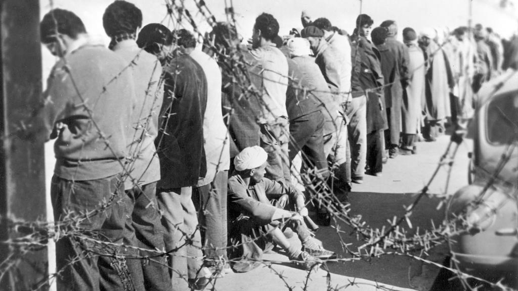 Festgenomme Algerier stehen im Dezember 1956 in Oran mit den Gesichtern zur Wand an der Stadtmauer und warten darauf, verhört zu werden; Foto: dpa/picture-alliance