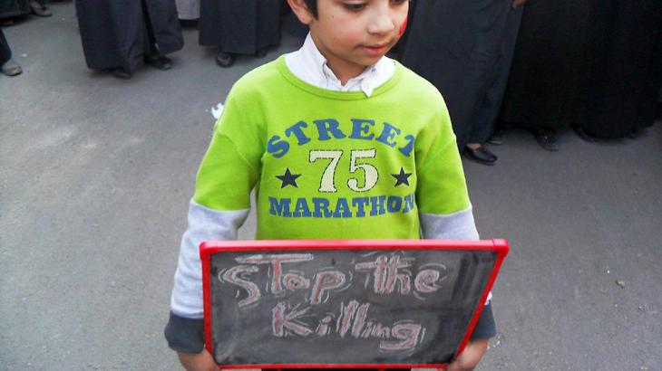 A child holds up a sign that reads "stop the killing" during an anti-Assad demonstration (photo: Reuters)