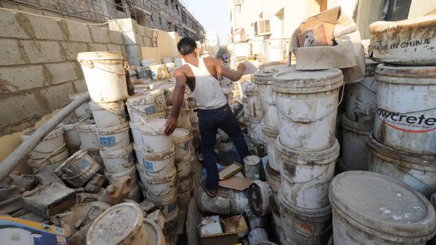 A foreign worker surrounded by empty paint pots (photo: picture-alliance/dpa)