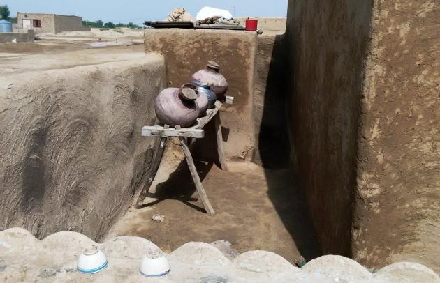 Jars used to carry water beside a clay house (photo: Usman Mahar)