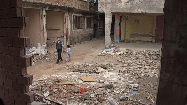 A man and child walk between rubble in the Sur neighbourhood of Diyarbakir (photo: DW)
