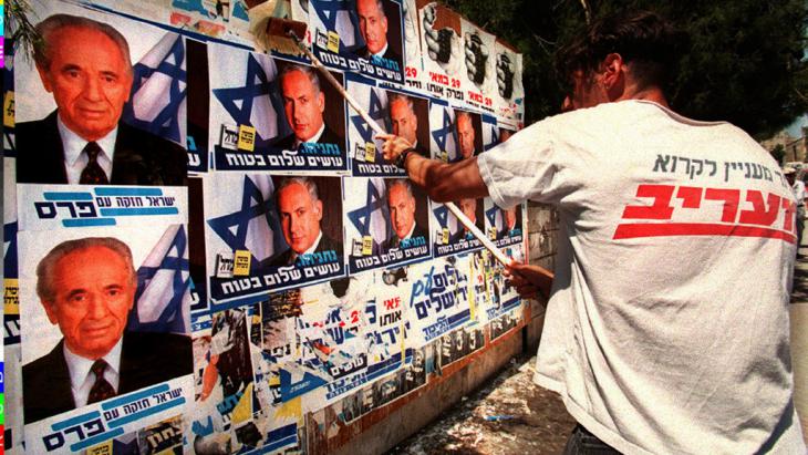An activist belonging to the right-wing Likud party covering over election posters belonging to Prime Minister Shimon Peres with those of Likud leader Benjamin Netanyahu on 26.05.1996 (photo: picture-alliance/COLORplus/P. Guyot)