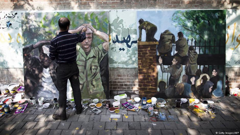 Iranian man puts the final touches to his painting outside the former U.S. embassy in Tehran, depicting the U.S. hostages following the storming of the embassy compound by Islamist students in 1979 (photo: Behrouz Mehri/AFP/Getty Images)