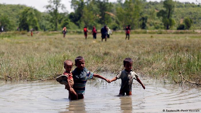 Rohingya children wade through water