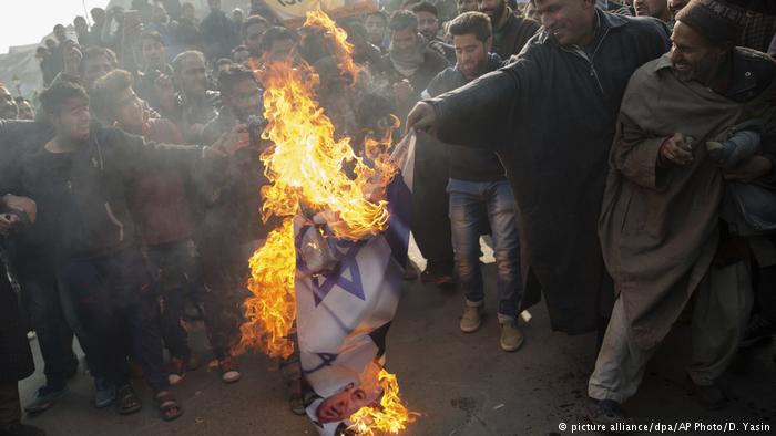 Muslim men burn Israeli and U.S. flags during a protest in Budgam, southwesst of Srinagar, in Indian-controlled Kashmir. Protesters marched in several places in Srinagar and other parts of the region after Friday prayers chanting slogans such as Down with America and Down with Israel (photo: picture-alliance/dpa/AP Photo/D. Yasin)