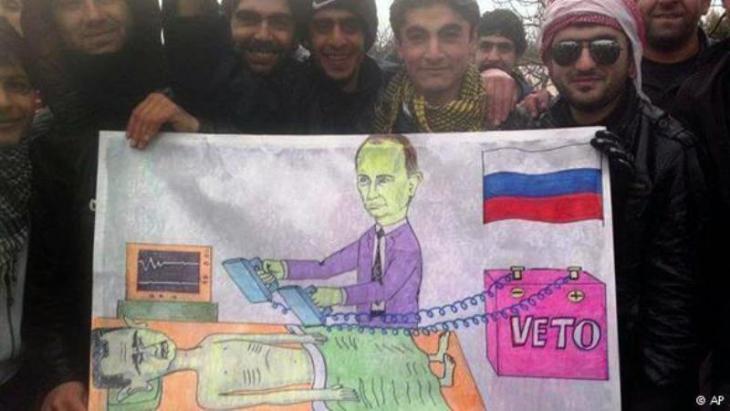 Activists from Kafranbel hold up a caricature of Putin keeping Assad alive (photo: AP)