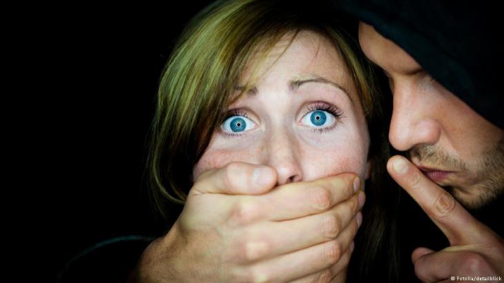 Symbolic image of violence against women and honour killings showing a man with his hand around a woman′s mouth (photo: Fotolia/detailblick)