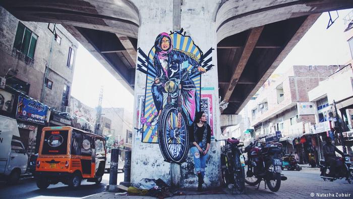 Fashion model Eman Suleman poses in front of graffiti by Shehzil Malik under a bridge in Lahore, Pakistan (photo: Natasha Zubair)