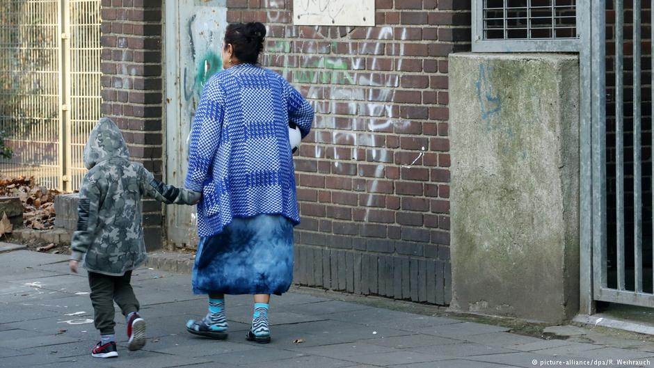 امرأة وطفل يمشيان ويمران بمنزل متهالك في حي ماركسلوه بمدينة دويسبورغ - ألمانيا 20 / 12 / 2016. (photo: Roland Weihrauch/dpa)