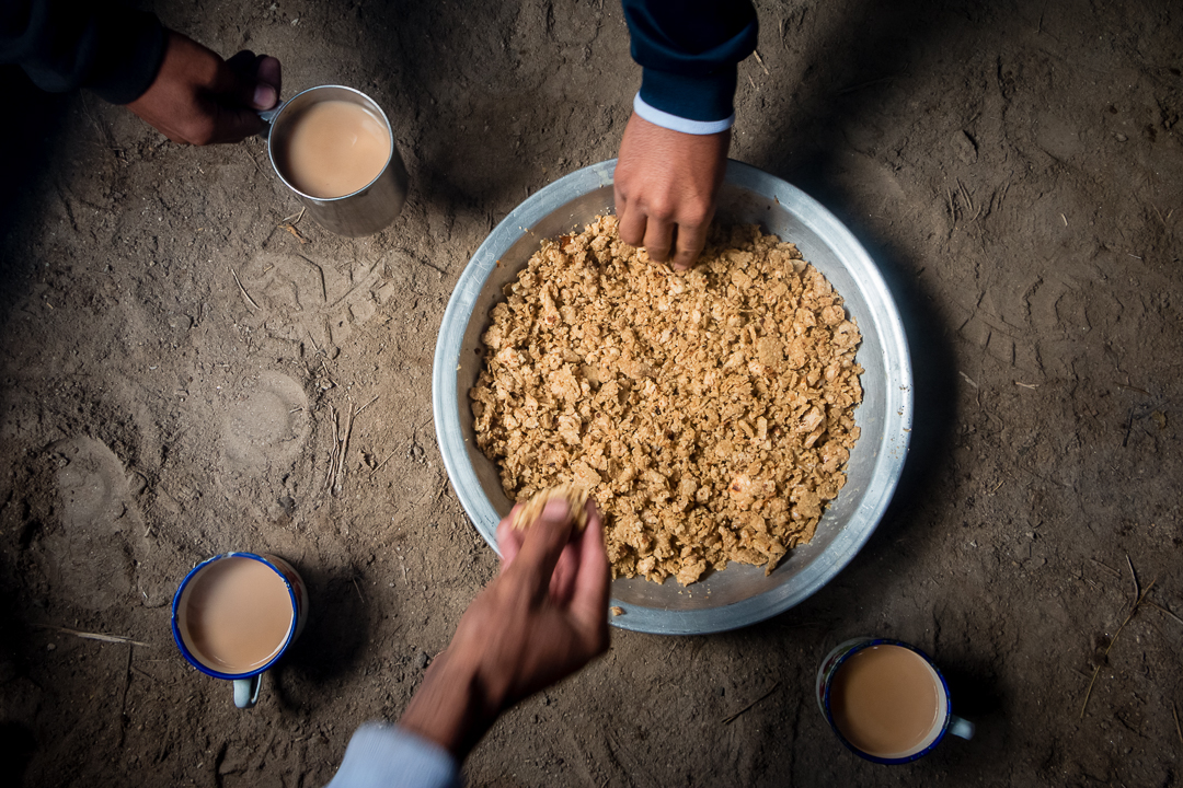 Men help themselves to "charmuk" and drink warm milk-tea in mugs (photo: Camille Del Bos)