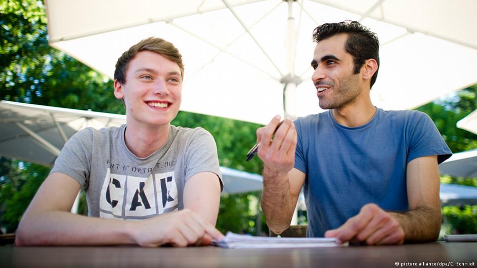 Student Tim Schwarz (left) gives Syrian refugee Renas Ottmann (right) German tuition in the grounds of the Goethe University in Frankfurt am Main on 30.06.2015 (photo: picture alliance/dpa/C. Schmidt)