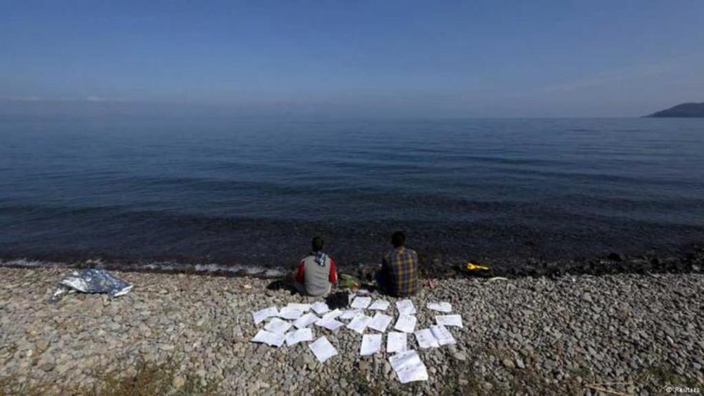 Zwei syrische Flüchtlinge trocknen ihre Dokumente an einem Strand auf der griechischen Insel Lesbos, 19. Oktober 2015 (Foto: Reuters/Yannis Behrakis).
