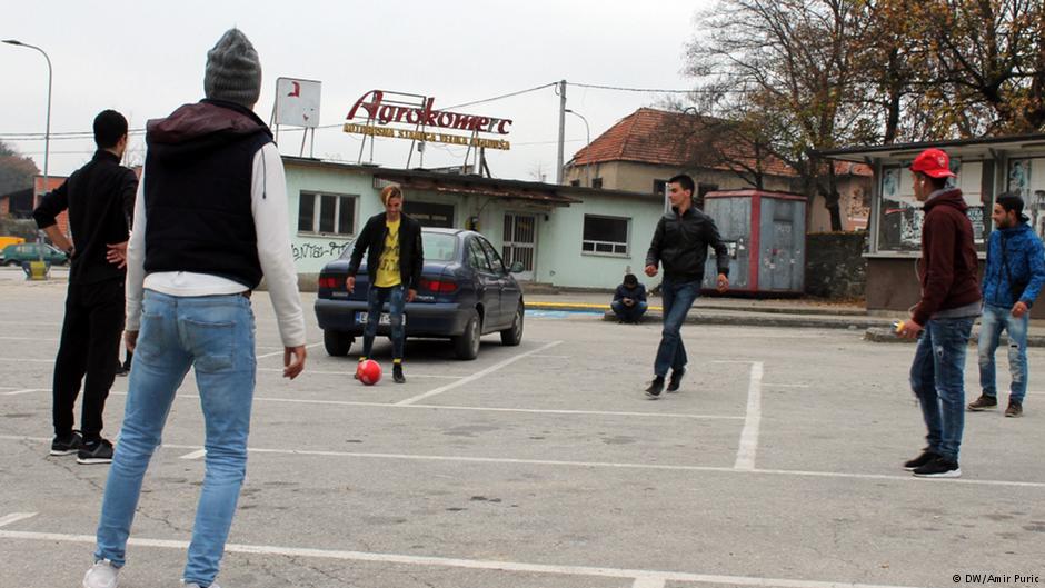 مهاجرون شباب يلعبون كرة القدم أمام محطة الحافلات في فليكا كلادوسا - البوسنة والهرسك