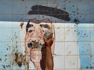 A Kurd destroys a tiled image of Saddam Hussein in northern Iraq following his overthrow in 2003 (photo: AP)