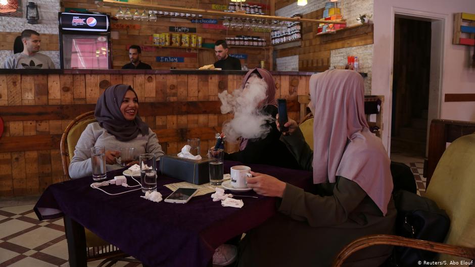 Student Saly Abu Amra (left), 23, a Sharia (Islamic law) and jurisprudence major, looks on as her friend smokes a water pipe at a cafe in Gaza City, 4 December 2018 (photo: Reuters/Samar Abo Elouf)