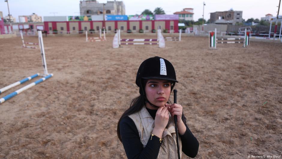 High school student Fatma Youssef adjusts her helmet as she prepares to ride a horse at an equestrian club in Gaza City (photo: Reuters/Samar Abo Elouf)